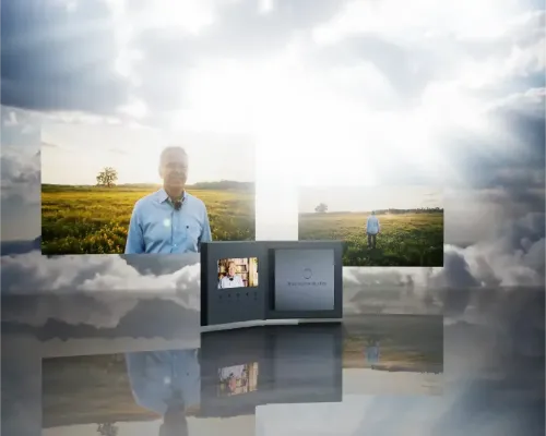 Geöffnete Premium-Videobox von „Was noch bleibt“ mit integriertem Display zur Filmwiedergabe vor einer atmosphärischen Wolken- und Feldkulisse.